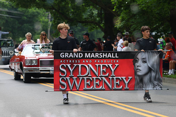 Banner is carried in front of the car driving Christy Martin and Grand Marshall actress Sydney Sweeney as they take part in the Parade of Champions on June 8, 2025 in Canastota, New York — frame 6/6 (612×408)